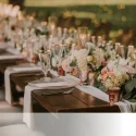 Destination wedding reception table setup with floral arrangements and candles.